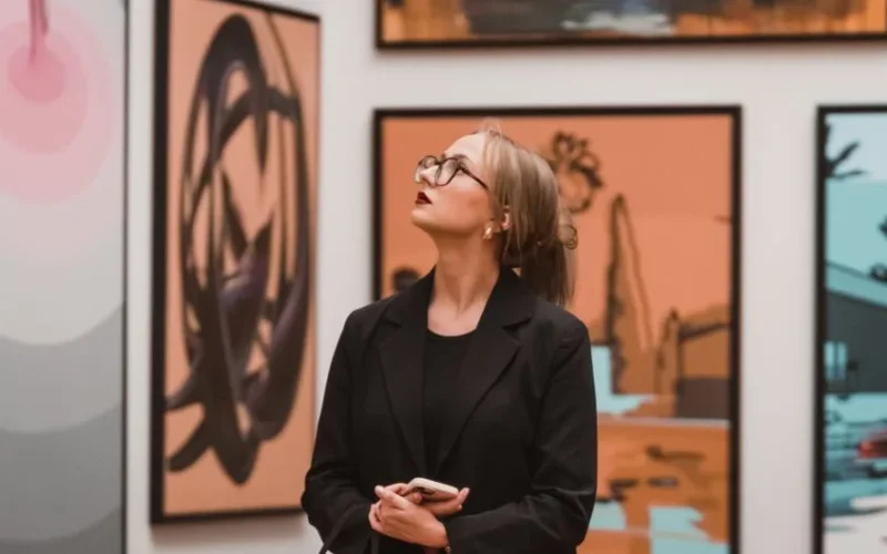 A woman in an art gallery thoughtfully observing modern artwork, reflecting creativity.