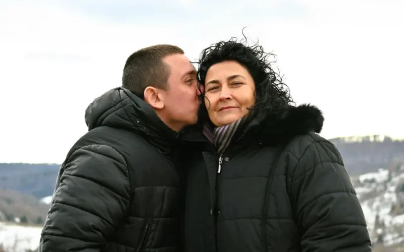 A heartwarming moment between a mother and son bundled up in winter coats outdoors.