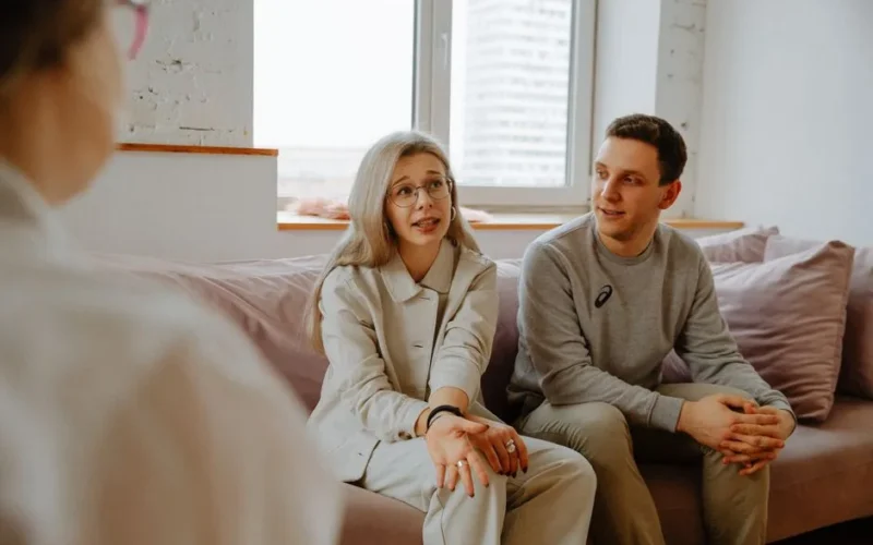 A couple and therapist engaged in a discussion during a therapy session indoors.