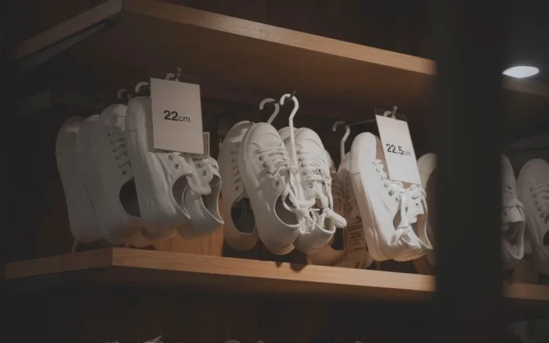 White sneakers elegantly displayed in a modern shop interior, showcasing minimalistic design on wooden shelves.