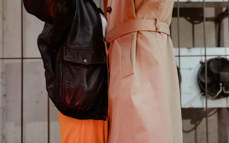 Close-up of a fashionable couple wearing leather jacket and trench coat embracing indoors.