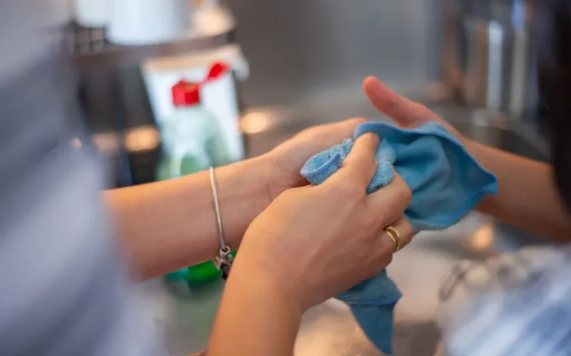 Detailed image of two people cleaning using a blue cloth indoors. Perfect for hygiene concepts.