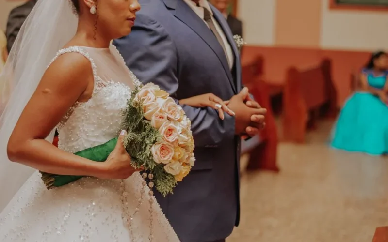 Bride holding bouquet standing next to groom during an elegant wedding ceremony indoors.