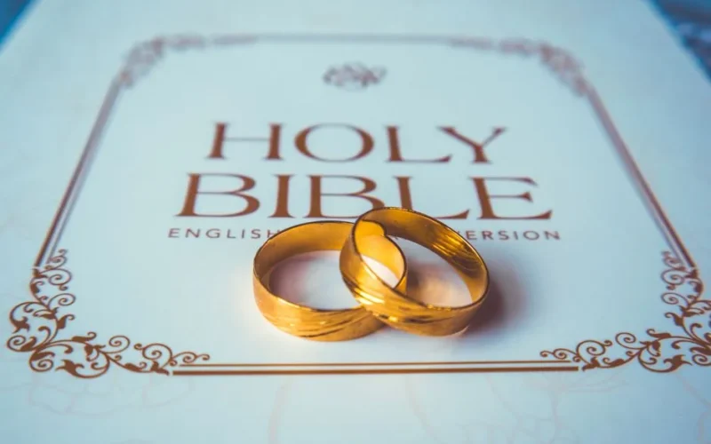 Two golden wedding rings placed on a Holy Bible, symbolizing a union rooted in faith.