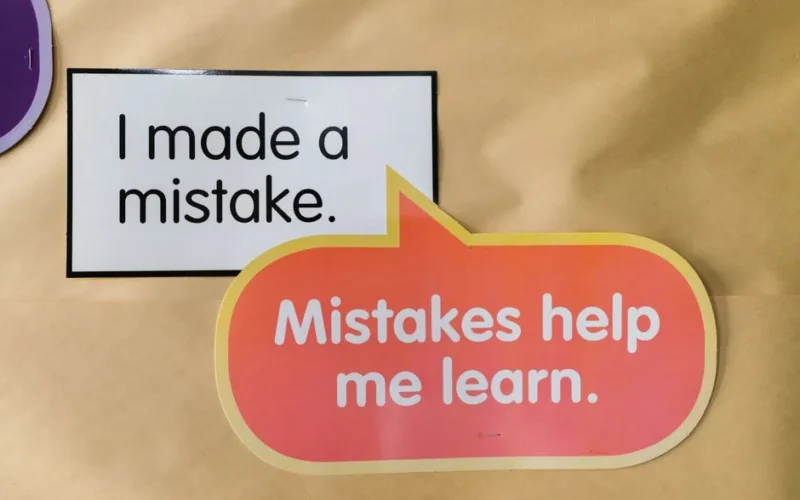 Bright square and speech bubble sign with motivational quotes about mistakes and learning.