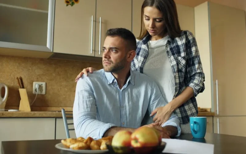 A thoughtful couple shares an emotional moment in a cozy kitchen setting.