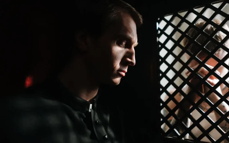 A contemplative priest listens to a confession in a dimly lit church setting, capturing a moment of faith and spirituality.