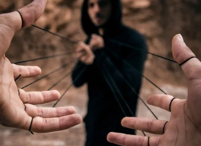 Conceptual image of a man controlling hands with strings, reflecting manipulation.