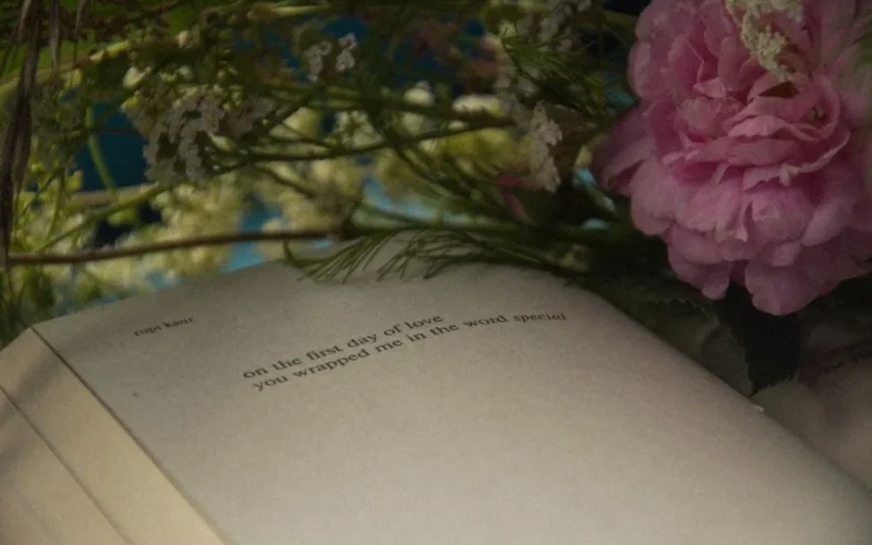 Open book surrounded by delicate flowers, creating a serene still life scene.