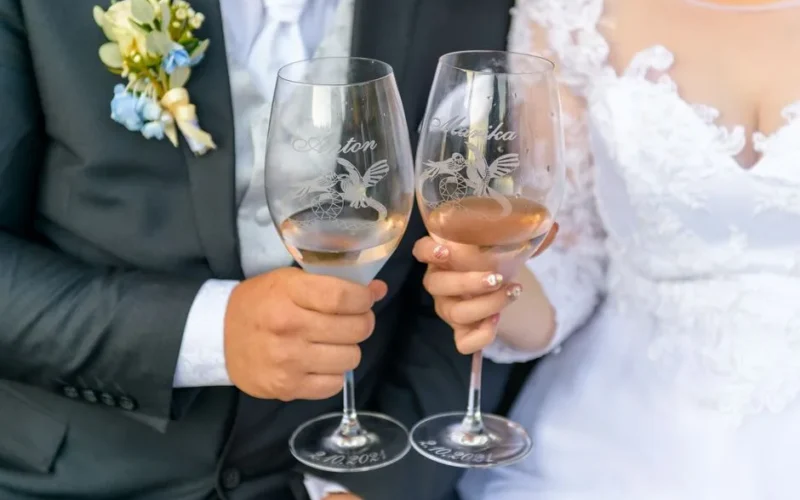 Close-up of a bride and groom toasting with wineglasses at their wedding celebration.