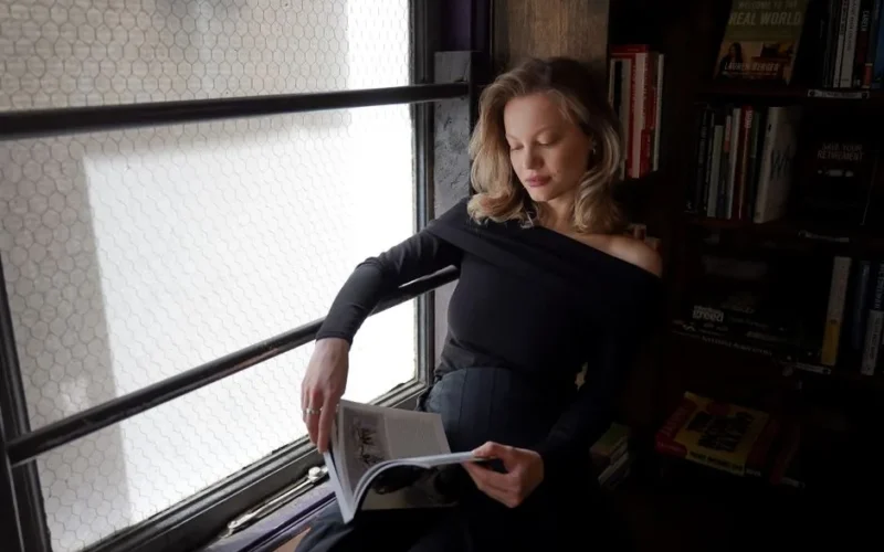 Woman reading by a window in a cozy bookstore setting, capturing a serene moment.