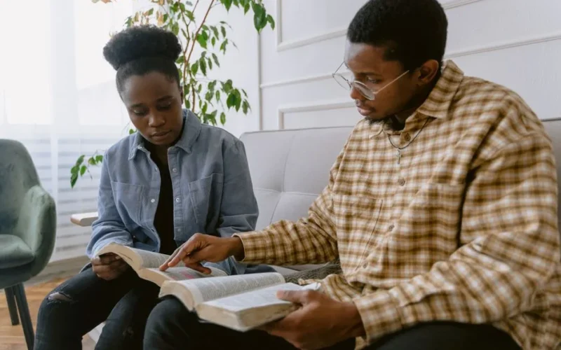 Two individuals engaged in reading the Bible together, depicting faith and togetherness.
