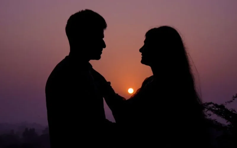 Silhouette of a couple embracing at sunset, capturing a romantic moment.