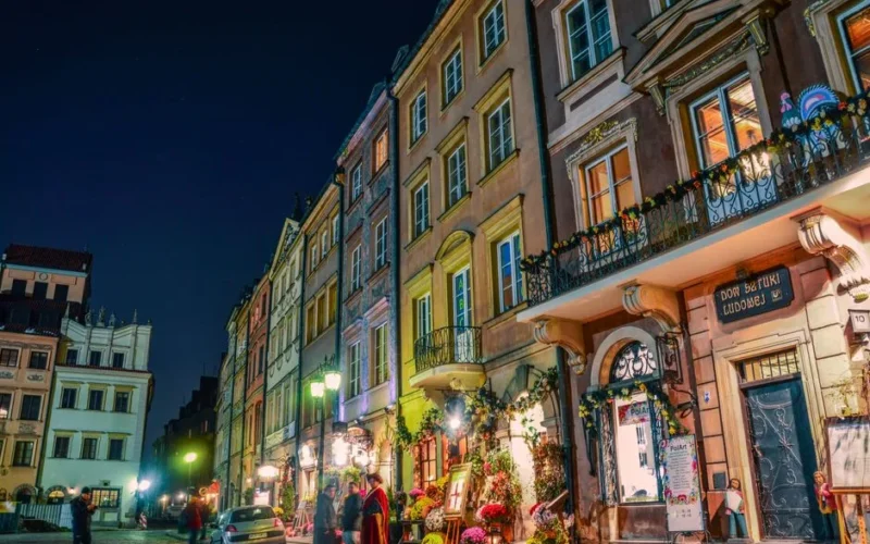 Charming night scene of Warsaw's historic Old Town filled with colorful buildings and lively streets.