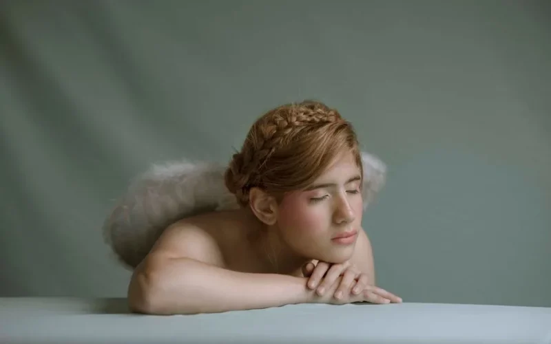 A portrait of a serene angelic figure with closed eyes and wings, embodying tranquility.