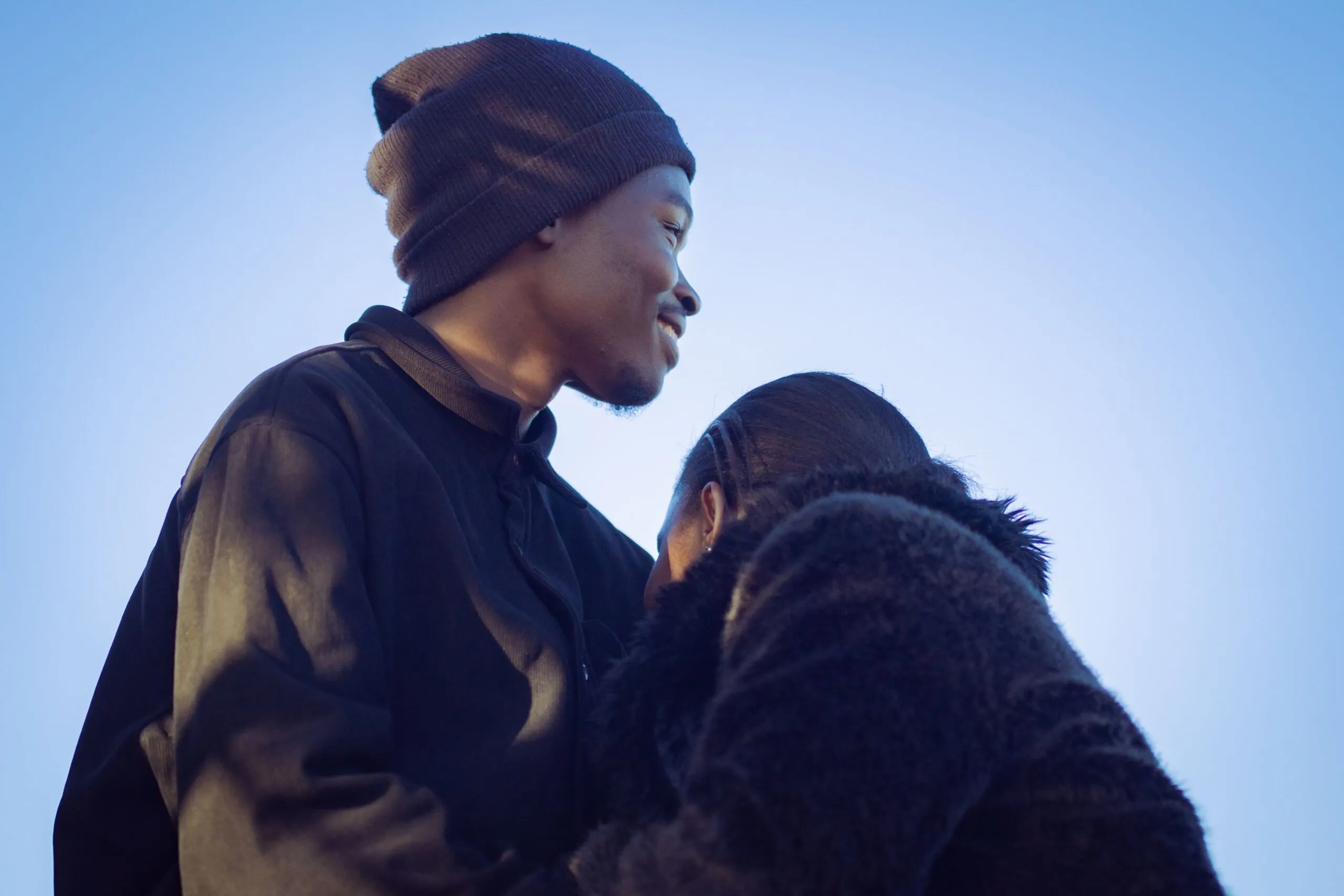 A tender moment between a young couple in Nairobi, reflecting love and warmth under a clear blue sky.