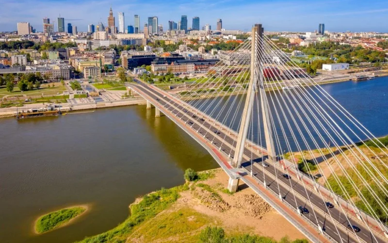 Stunning aerial shot of Świętokrzyski Bridge spanning the Vistula River in Warsaw, Poland, with the city skyline.
