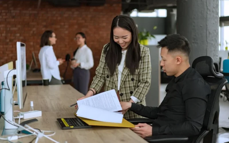 Professionals engaged in teamwork at a modern office desk reviewing documents.