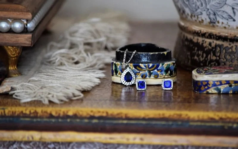 Close-up of elegant jewelry including earrings and pendant on a rustic table setting.