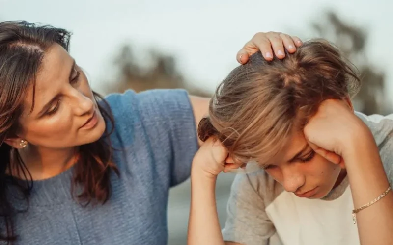 A mother offers support to her discouraged teenager son, portraying love and understanding.