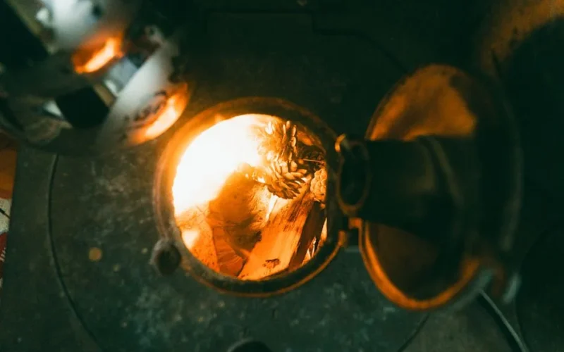 A cozy view inside a vintage wood stove with burning logs and firelight creating a warm ambiance.