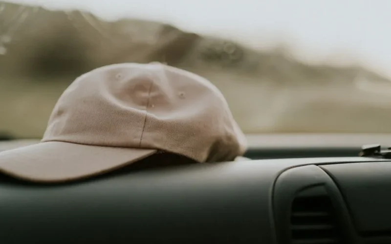 Minimalistic scene of a beige cap on a car dashboard, offering a sense of travel and style.