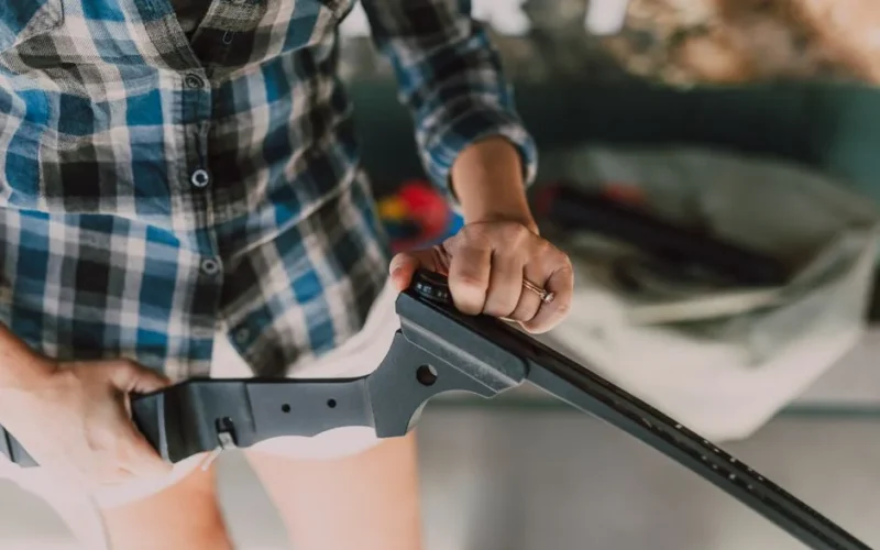 Detailed view of a person assembling a rifle indoors. Focus on hands and equipment.