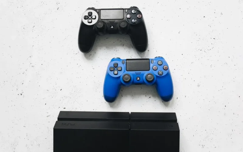 Two game controllers placed on a white surface above a gaming console.