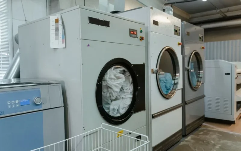 Interior view of industrial laundry machines in a facility with linens being washed.