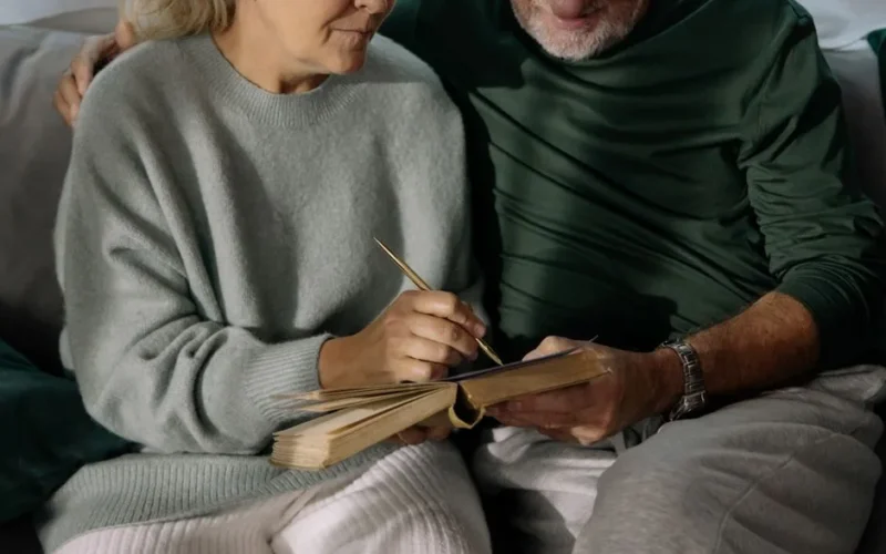 Elderly couple writing together in a cozy living room, sharing memories and affection.