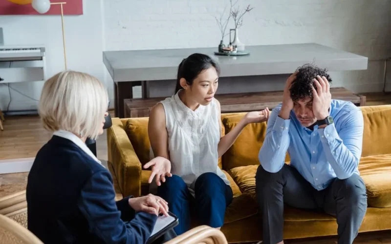 A couple having a therapy session with a psychologist in a modern office setting.
