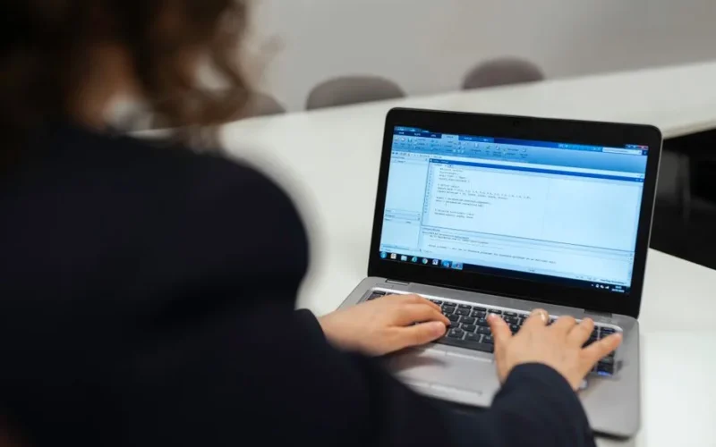 Focused woman coding on a laptop in a modern office setting.