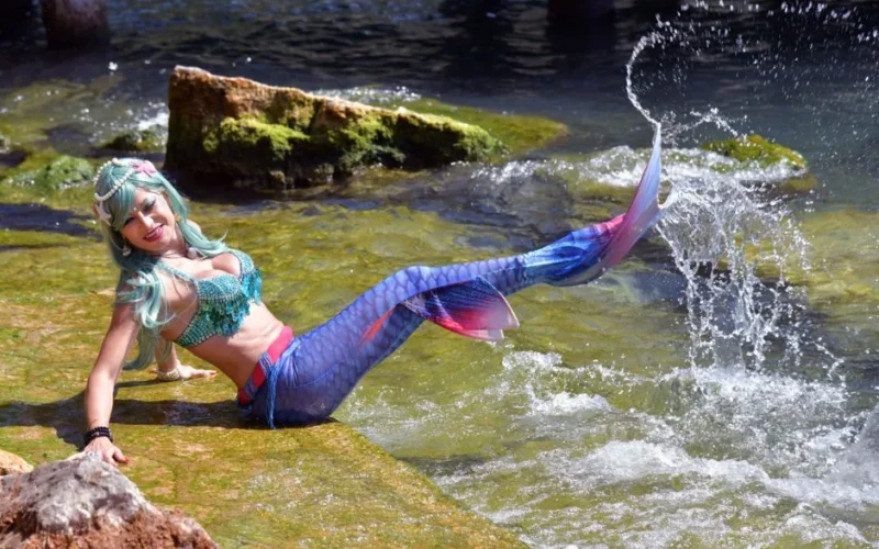 Colorful mermaid costume model splashing water in Garda, Italy.