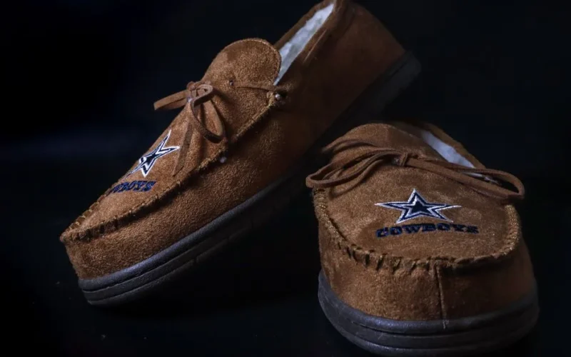 Brown suede loafers with star embroidery, close-up shot with elegant black background.