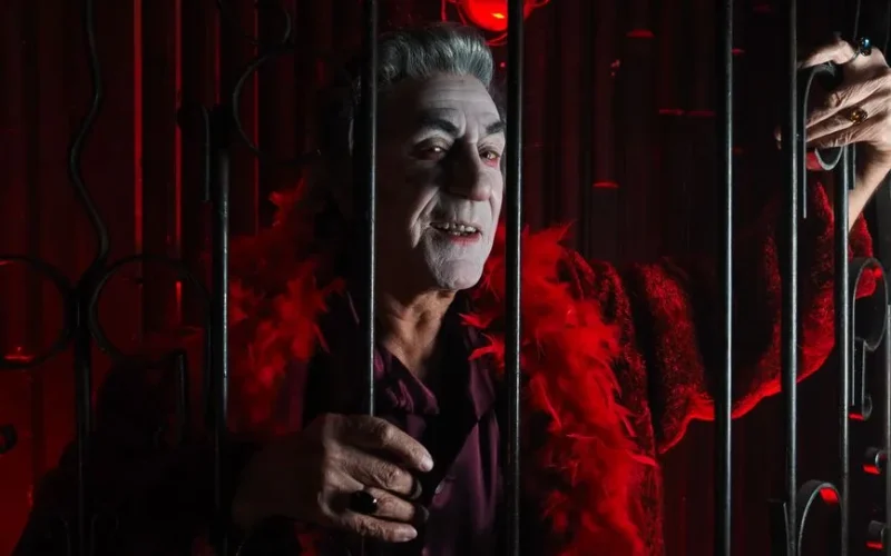 A spooky vampire in a red costume behind bars, perfect for Halloween and festive themes.