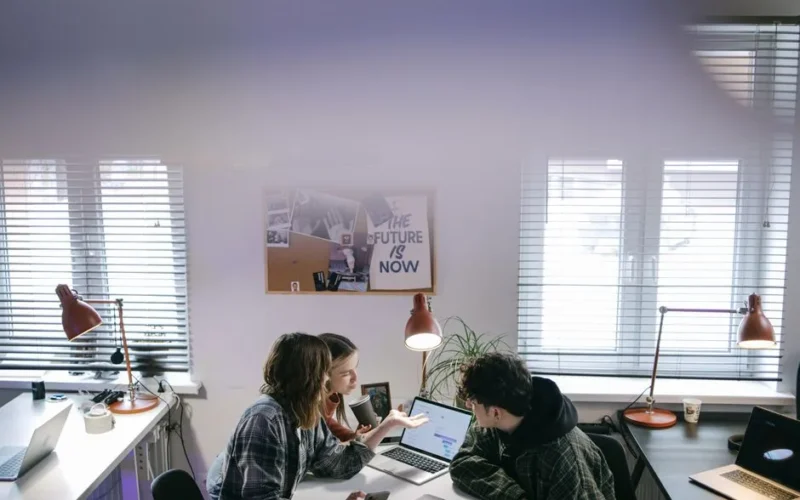 A group of people discussing ideas around laptops in a bright, modern office space.