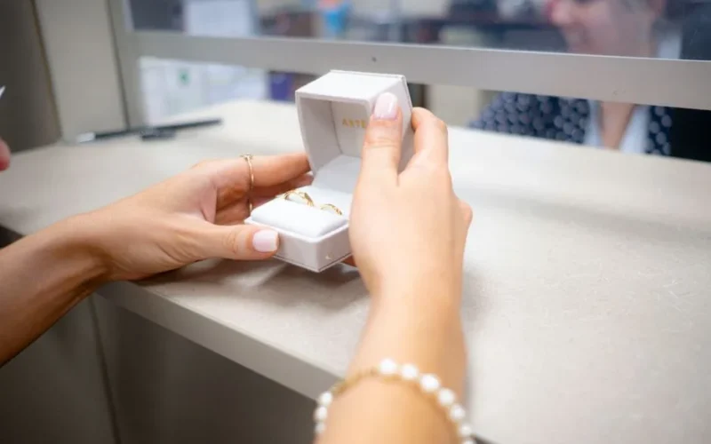 Close-up of hands holding an open jewelry box over a counter indoors.