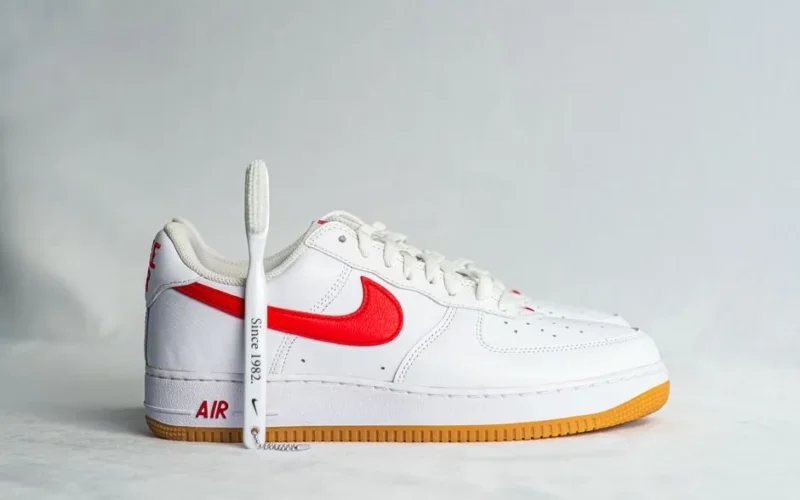 Detailed view of a white sneaker with red swoosh and gum sole.