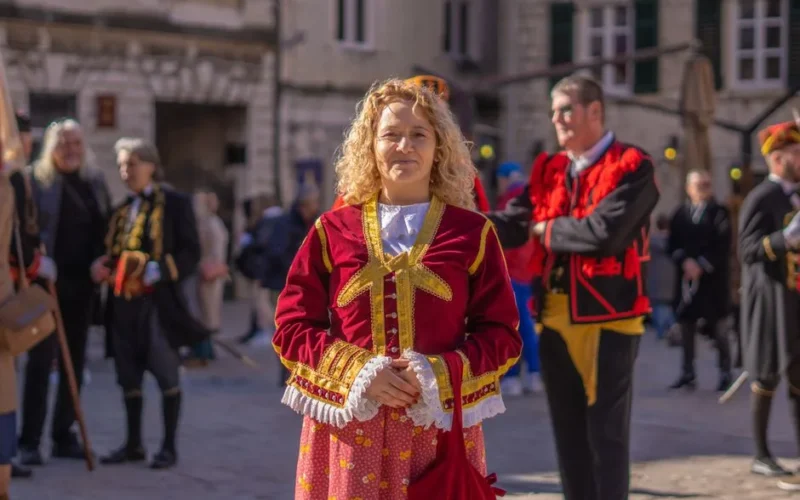 Woman in vibrant historical costume participates in an outdoor festival.