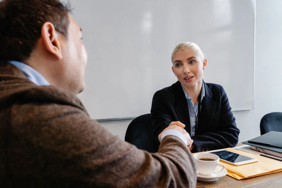 Diverse coworkers in formal wear sitting in workspace and shaking hands after successful business plan