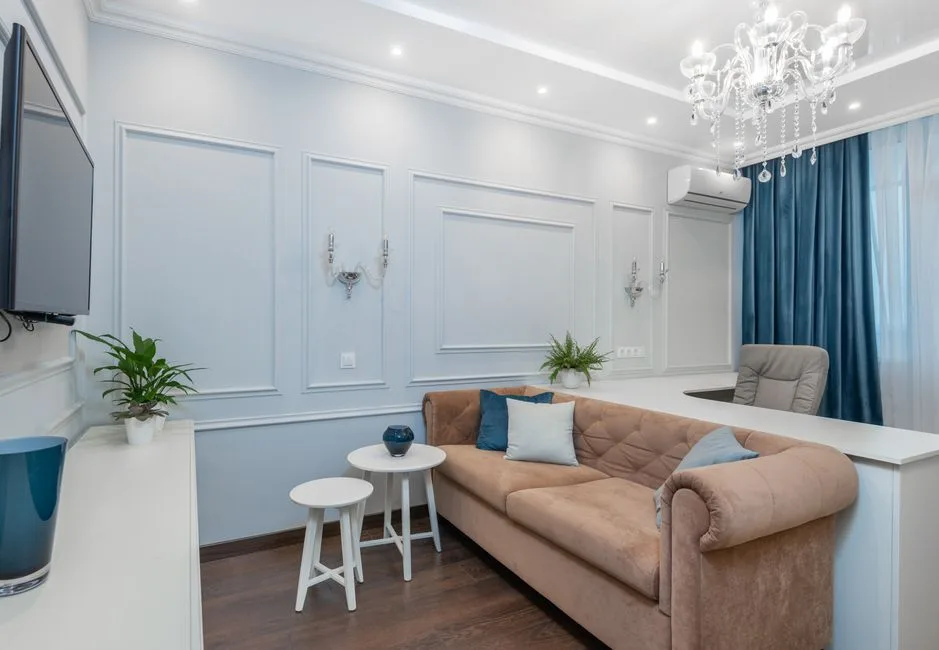 Jasny, elegancki salon z żyrandolem, wygodną kanapą i stylowymi dekoracjami