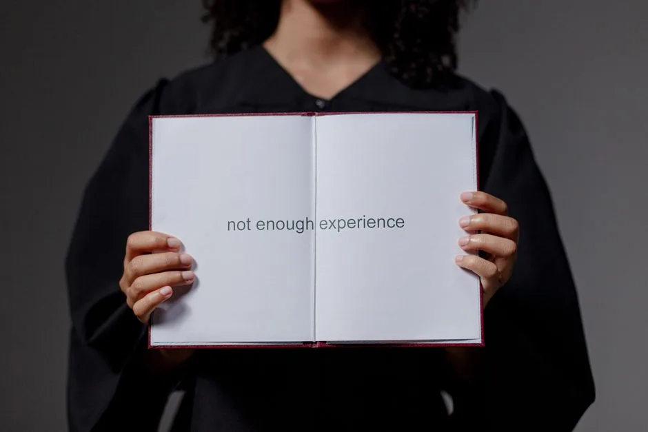 Absolwent w todze i czapce prezentuje dyplom z napisem not enough experience, ukazując wyzwania rynku pracy